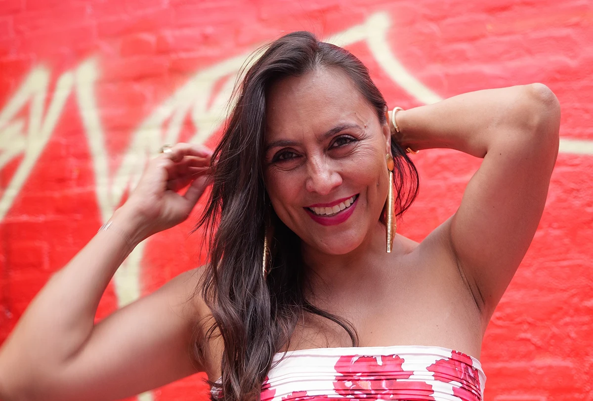 Medium close-up portrait of a woman in natural light, in contrast with a bright red blurred background.