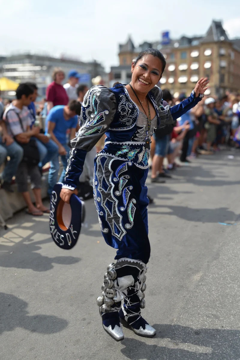 Young woman performing Bolivia’s Caporal dance at Rådhusplads in Copenhagen, wearing traditional male costume instead of female attire.