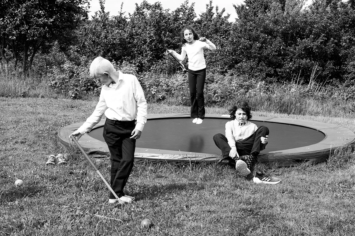 Three young children jumping in the trampolin and enjoying the good weather for a party.
