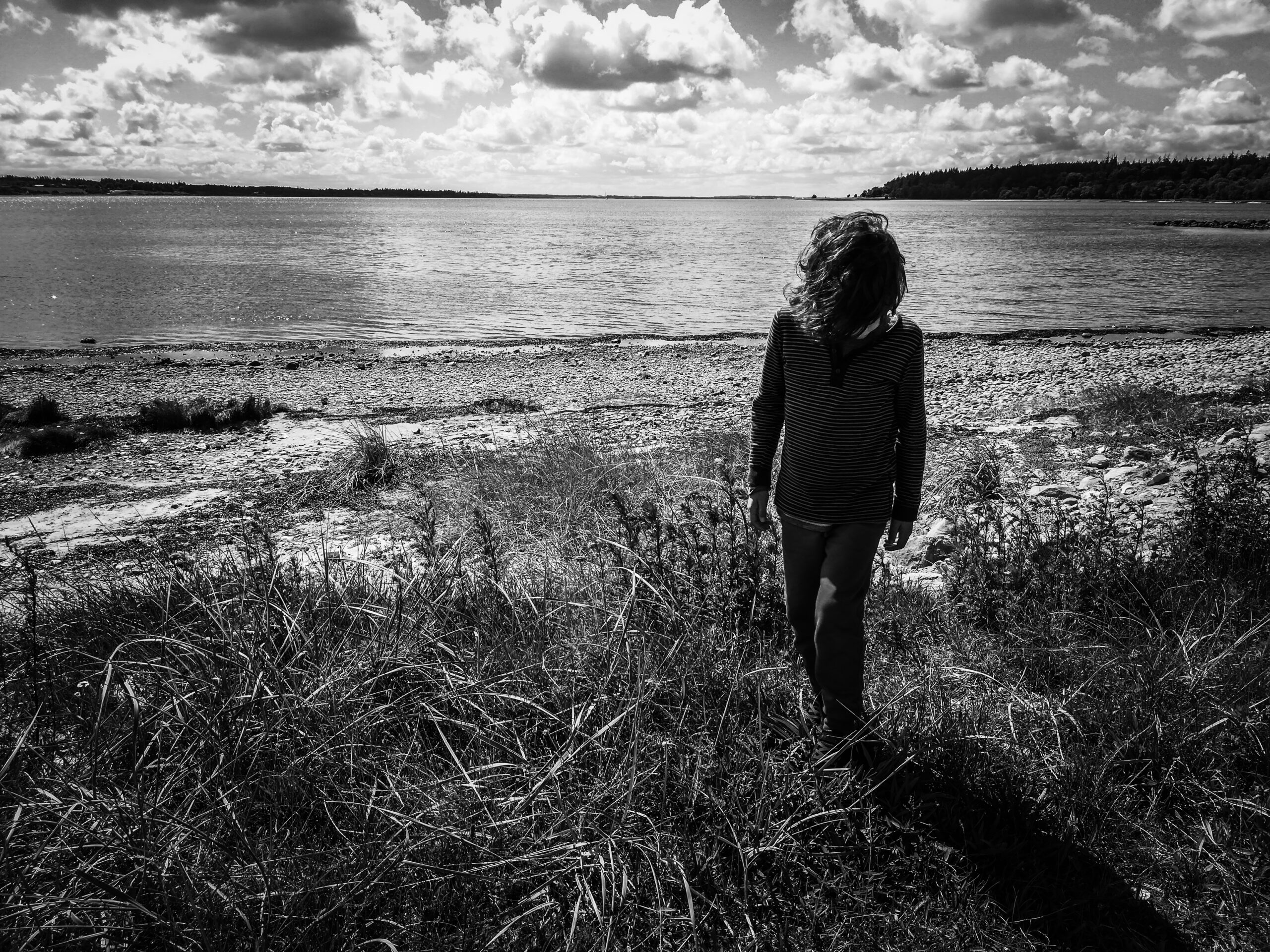 Boy walking on the beach with horizon in the back.