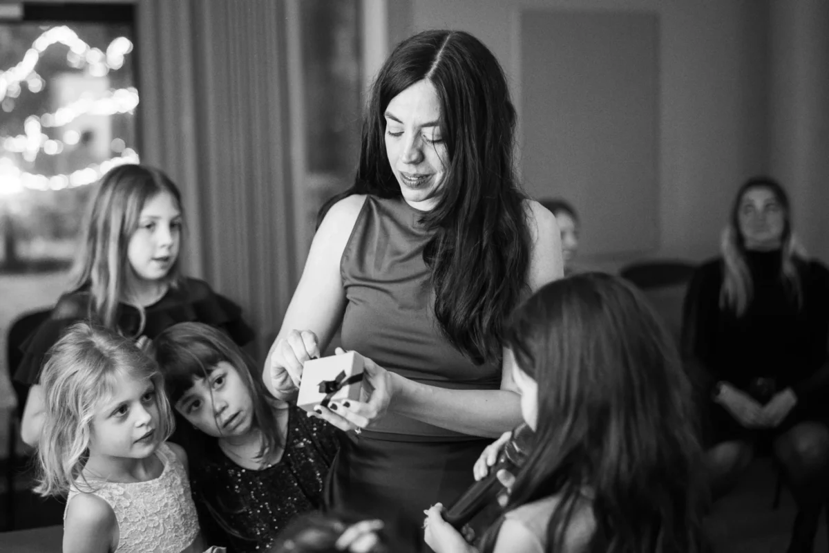 Woman opening a gift surrounded by curious children.
